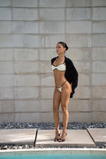 White and black trim bikini styled with draped black cardigan by pool
