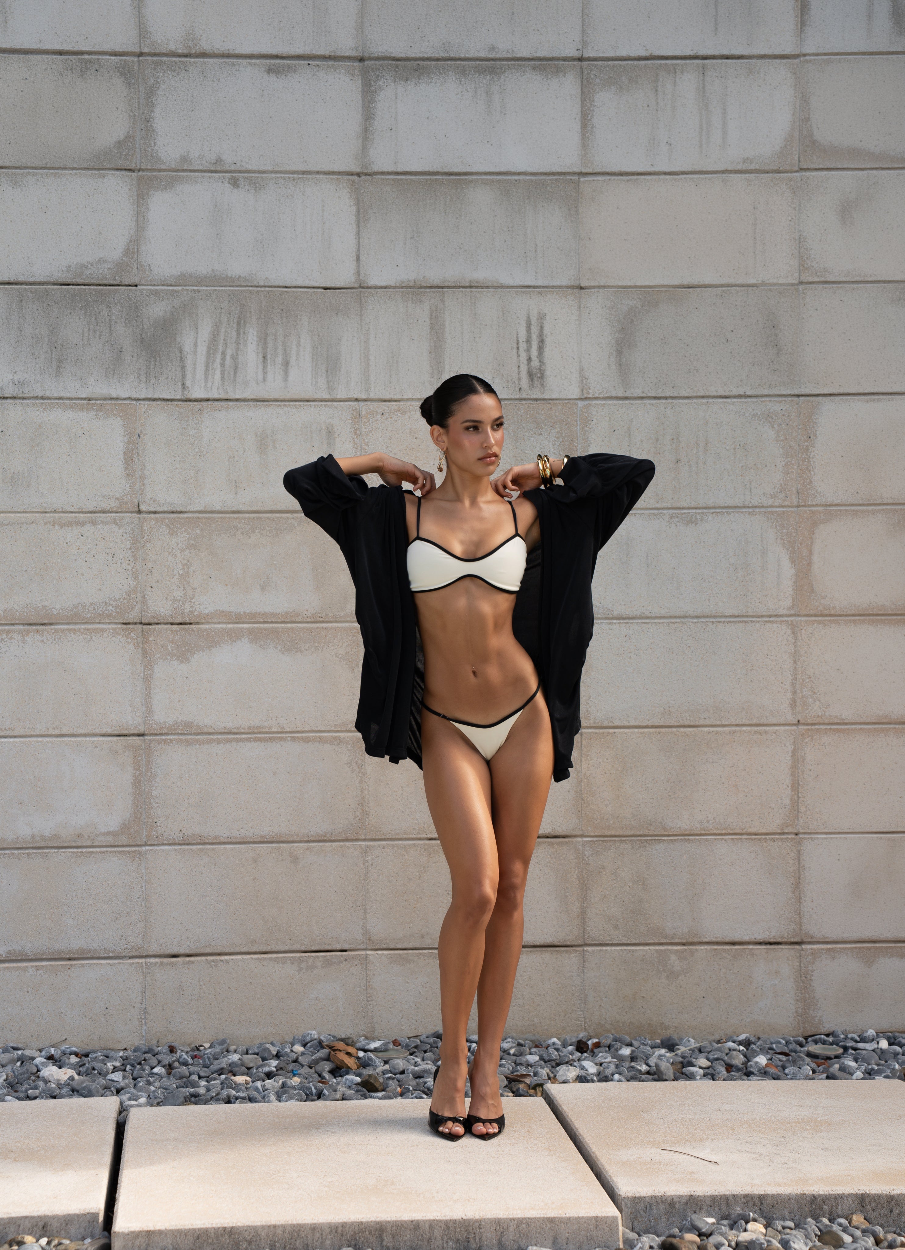 White bikini with black trim layered under open black cardigan