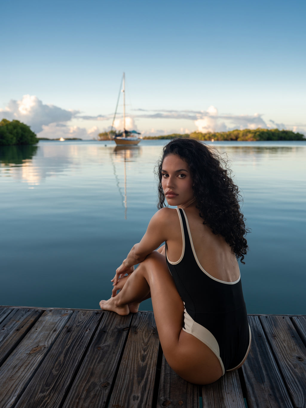Windy Suil Luz black one-piece swimsuit with cream trim on wooden dock